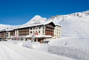 A hotel with multiple floors, a prominent mountain in the background, and snow-covered surroundings.