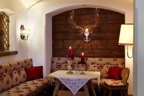 A cozy room with a wooden ceiling, a wall-mounted deer head decoration, and a table with candles and a glass vase.
