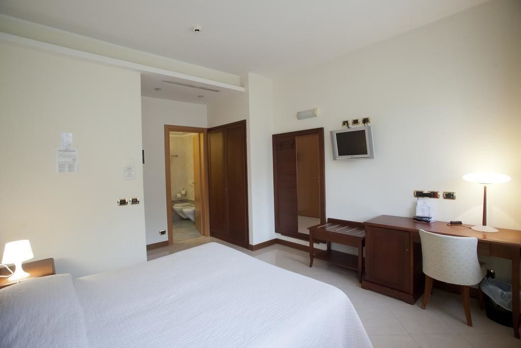 Una habitación de hotel con cama, escritorio, silla y televisor.