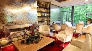 Una sala de estar moderna con chimenea, sillas blancas y un ventanal con vistas a la vegetación.