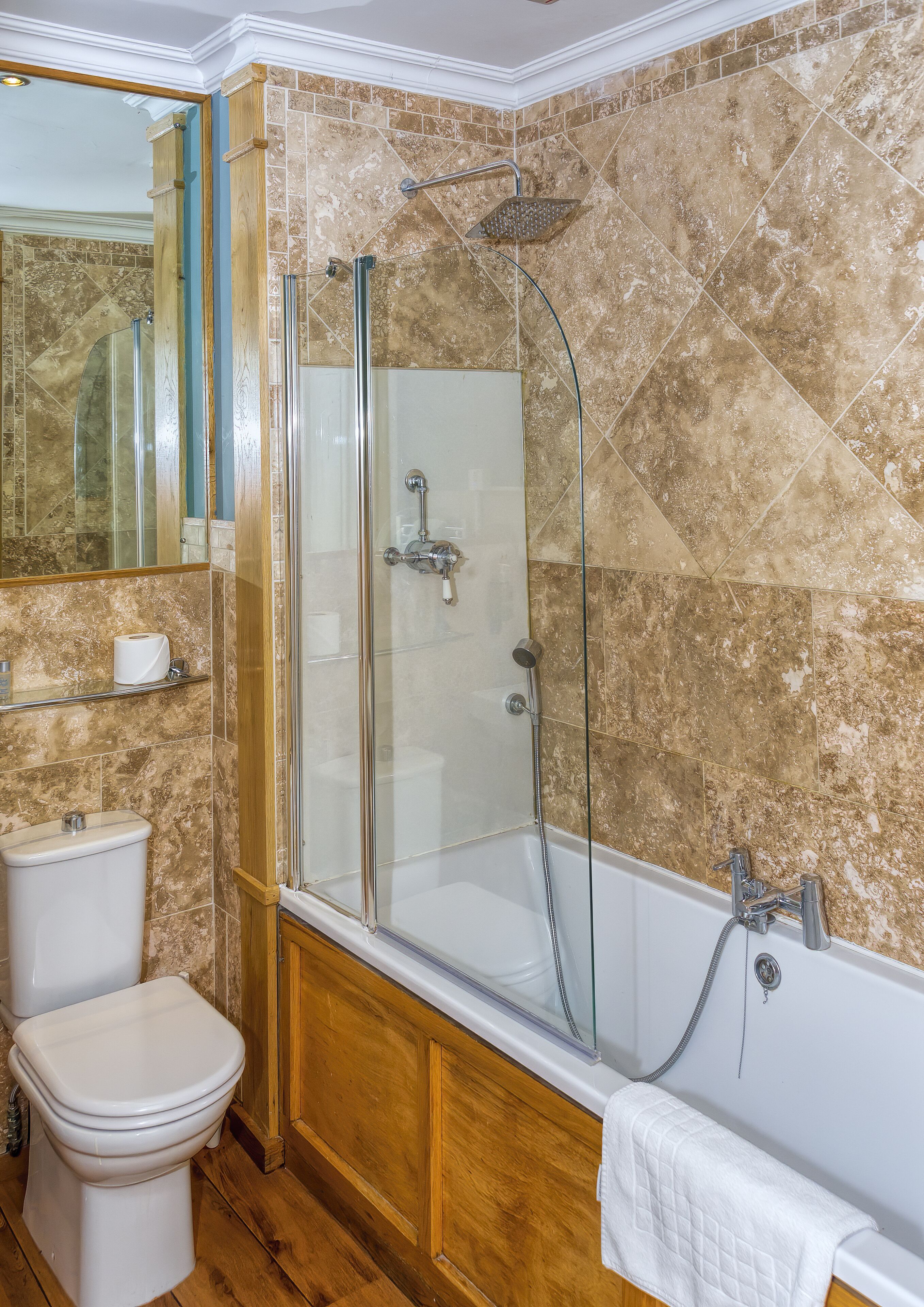 A bathroom with a glass-enclosed shower, a bathtub, a toilet, and a mirror.