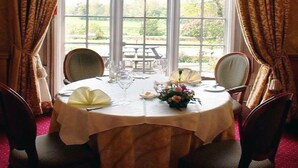 Mesa de comedor para cuatro con vistas a un jardín a través de amplios ventanales.