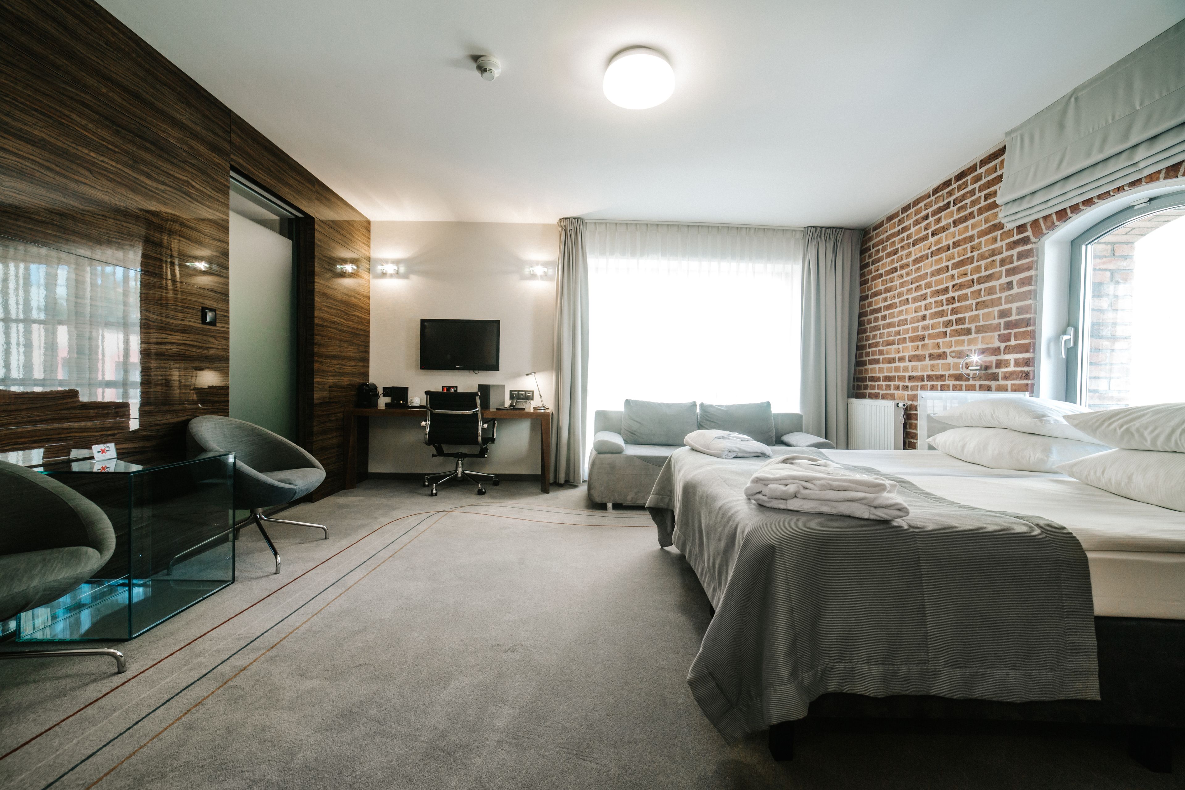 Une chambre d’hôtel moderne équipée d’un lit, d’un bureau, d’une chaise et d’un téléviseur.