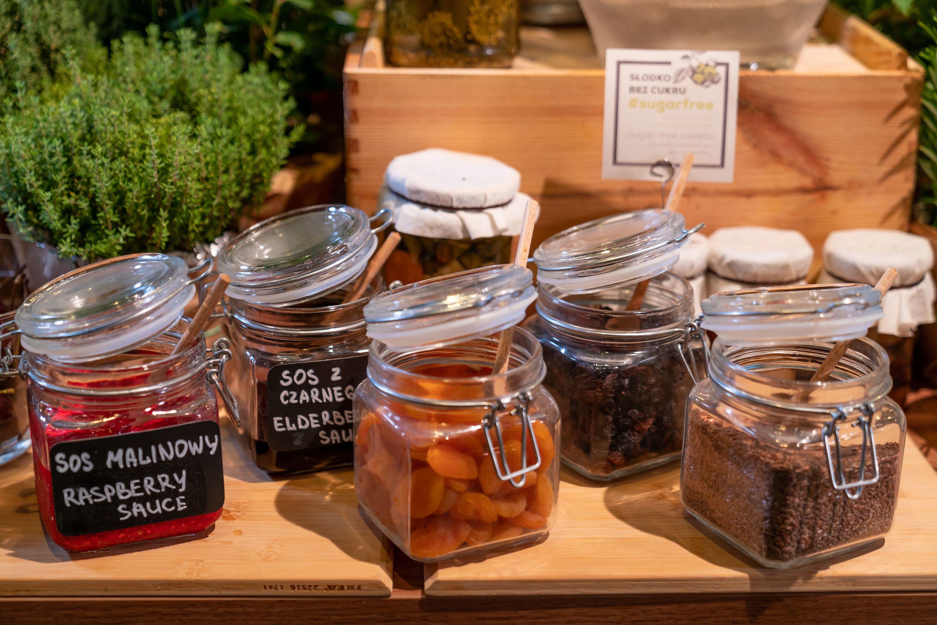 A display of various food items in glass jars with labels, including a raspberry sauce and elderberry sauce.