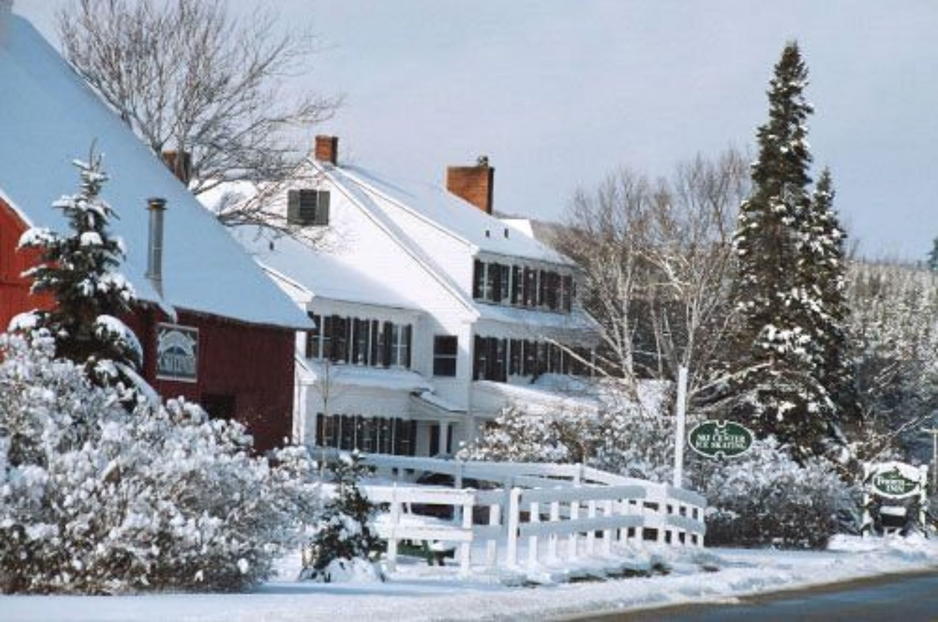 A snow-covered two-story building with a white exterior and a red section on the left.