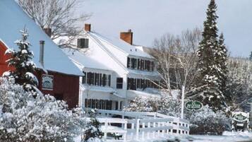 A snow-covered two-story building with a white exterior and a red section on the left.