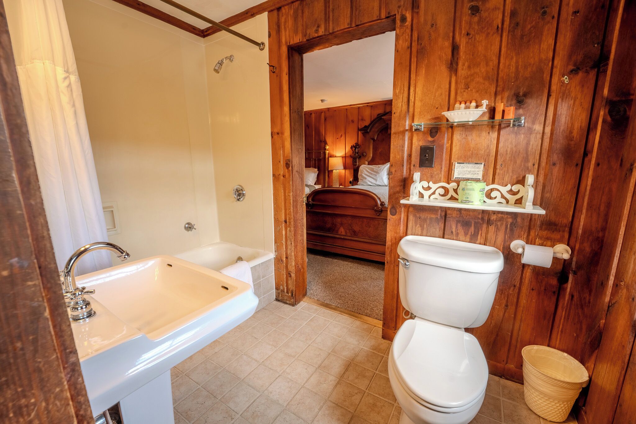 A bathroom with a sink, toilet, and wooden walls.