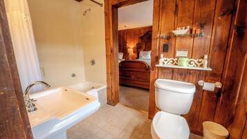 A bathroom with a sink, toilet, and wooden walls.