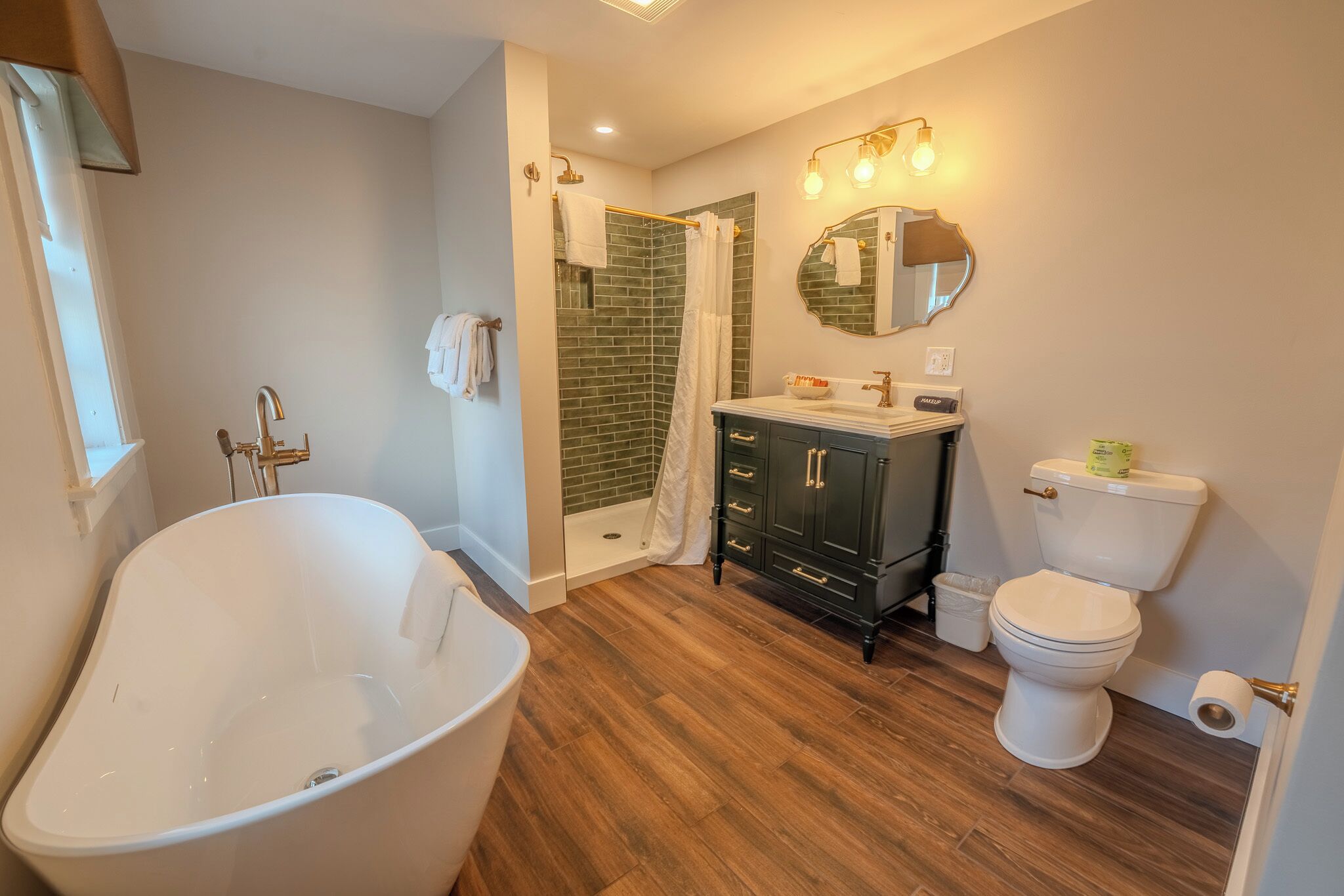 A bathroom with a freestanding bathtub, a shower with a glass door, a toilet, and a vanity with dark cabinets.