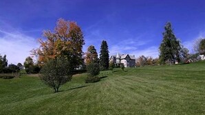 A well-maintained lawn with a few trees and a large building in the background. - Margaretville Mtn Inn B&B and Village Suites (Margaretville)
