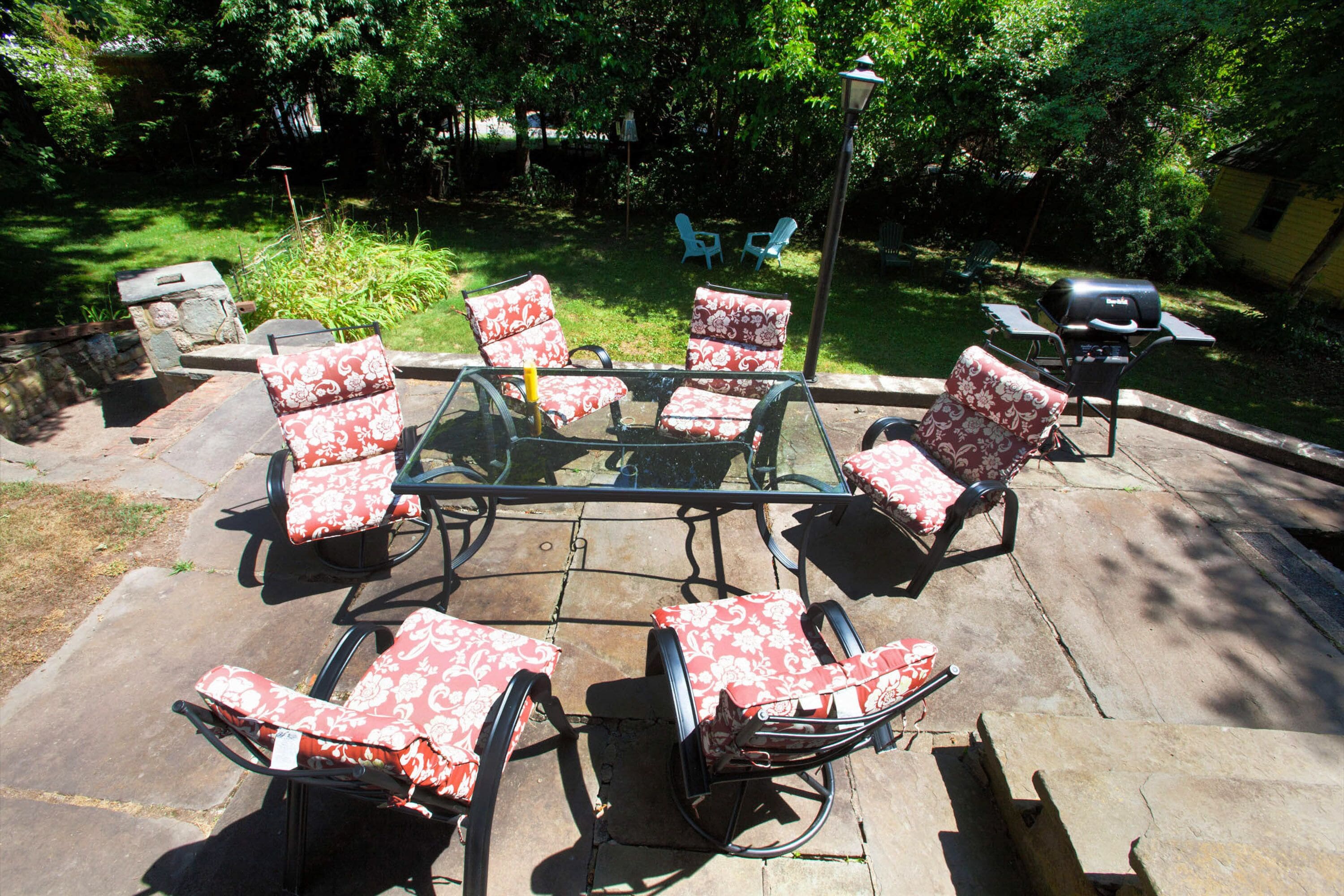 A patio with a glass-top table surrounded by four chairs with floral upholstery.