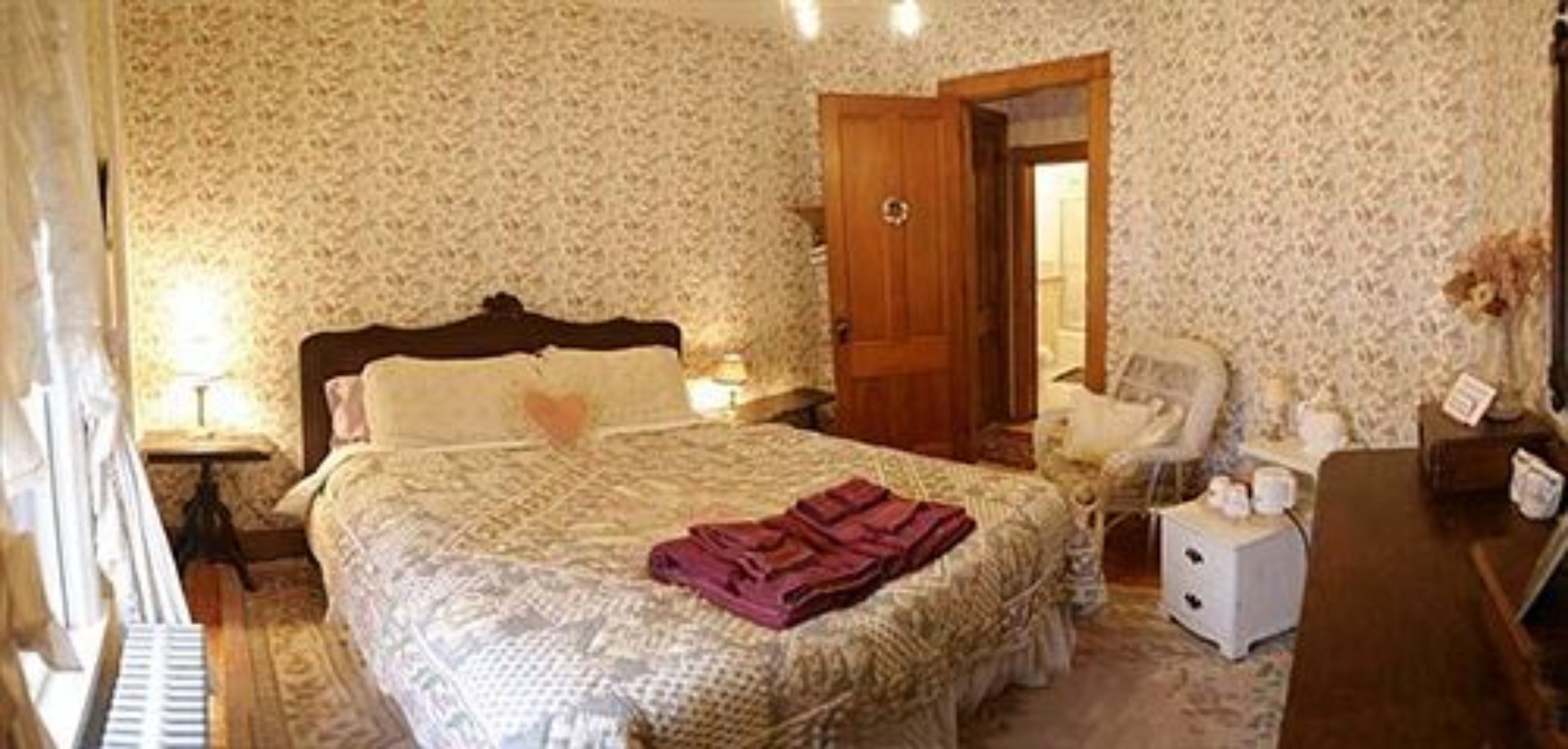 A bedroom with a bed, a nightstand, a chair, and a dresser.