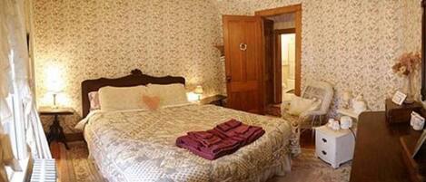 A bedroom with a bed, a nightstand, a chair, and a dresser.