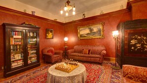A room with a chessboard, a sofa, a bookshelf, and a patterned carpet. - Margaretville Mtn Inn B&B and Village Suites (Margaretville)