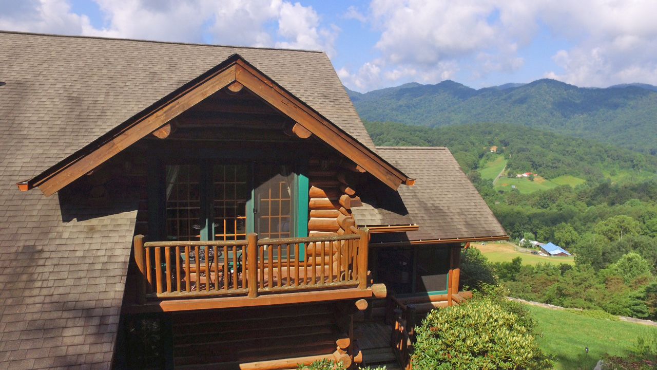 A log cabin with a balcony and a view of a mountainous landscape.