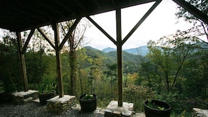 A covered outdoor area with stone steps leading to a view of a forested mountain range. - Wildberry Lodge (Leicester)
