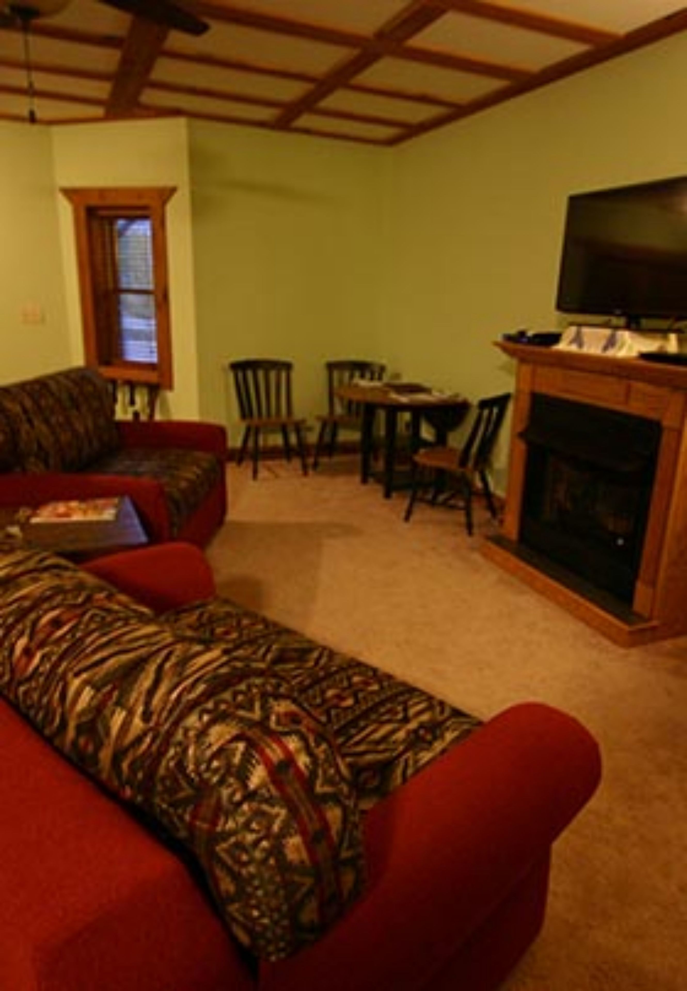 A living room with a sofa, chairs, a fireplace, and a television.