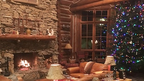 A cozy living room with a stone fireplace, leather sofas, a Christmas tree, and a wine rack. - Wildberry Lodge (Leicester)