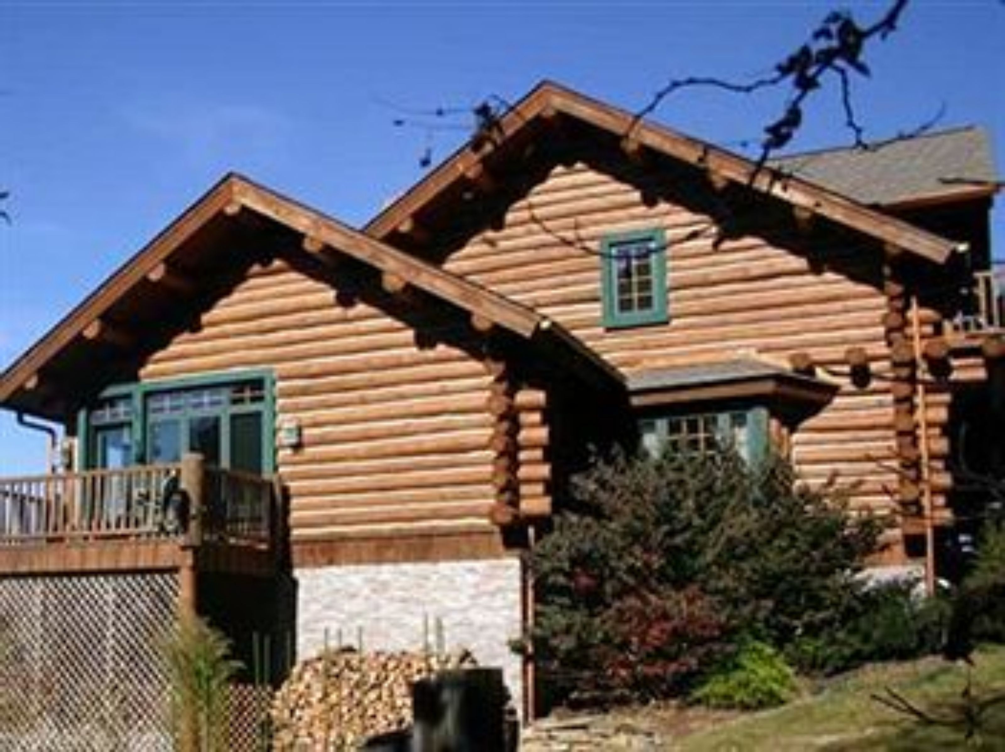 A log cabin with a balcony and a stone foundation.