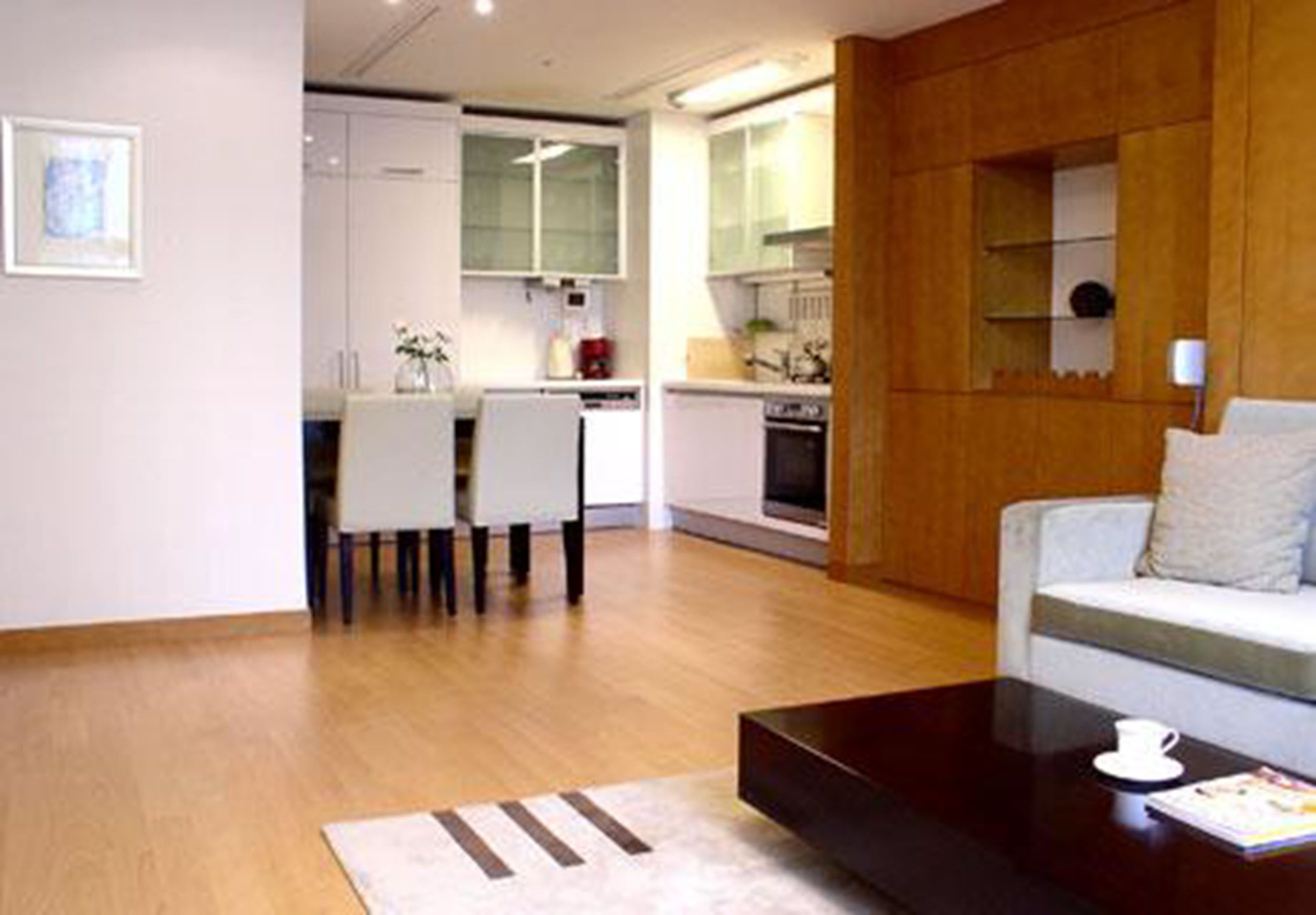 A modern living room with a sofa, a coffee table, and a dining area with chairs and a table.