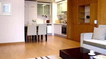 A modern living room with a sofa, a coffee table, and a dining area with chairs and a table.