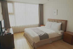 A hotel room with a bed, a bedside table, a TV, and a window with curtains. - Vabien Suite 1 Serviced Residence (Seoul)