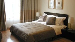 Een hotelkamer met een groot bed, twee bedlampen en een raam met gordijnen.