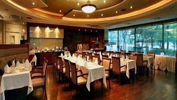 Een restaurant met een rond plafond, houten vloeren en tafels gedekt met witte tafelkleden.