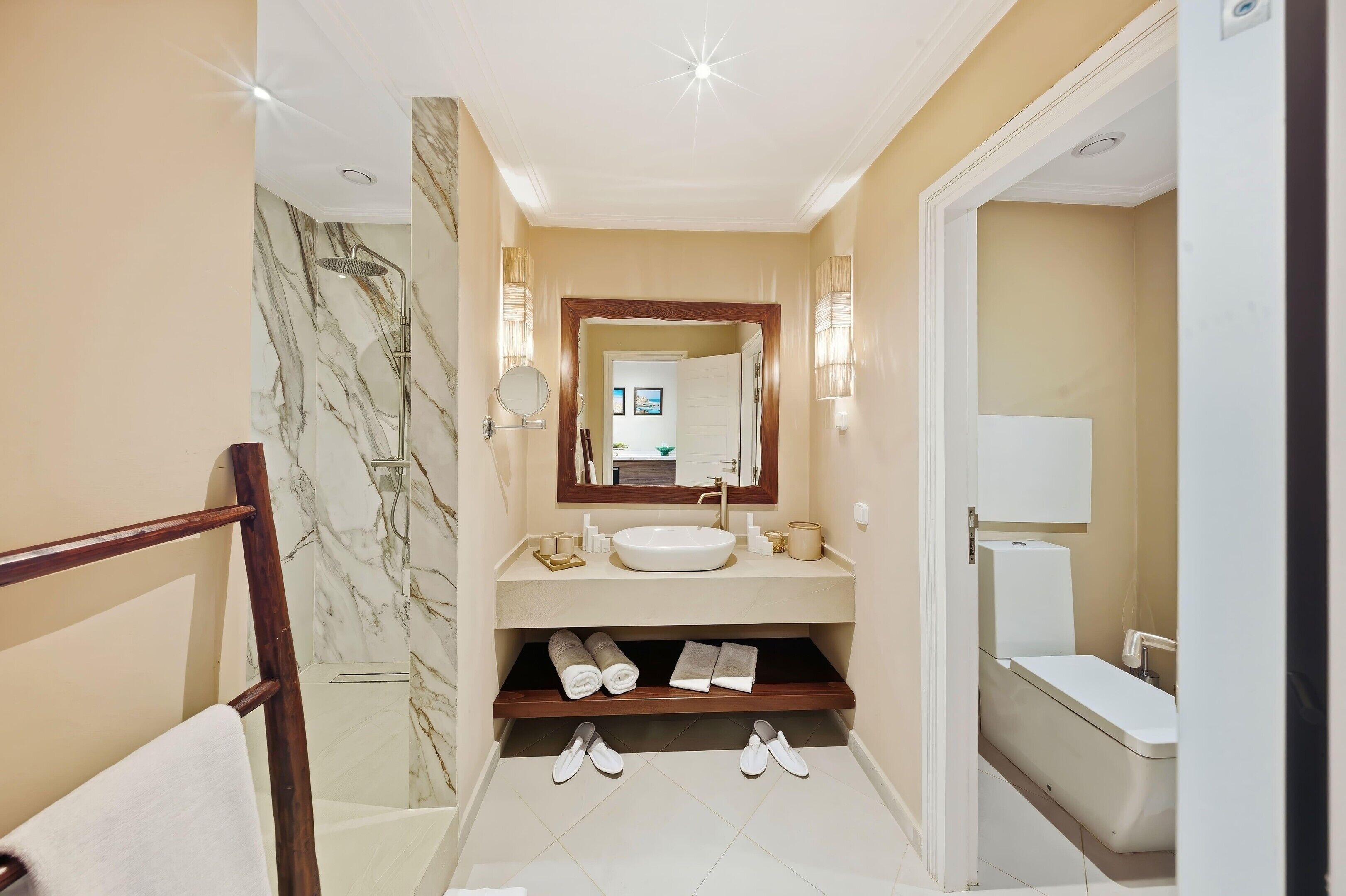 A bathroom with a marble shower, a sink, and a toilet.