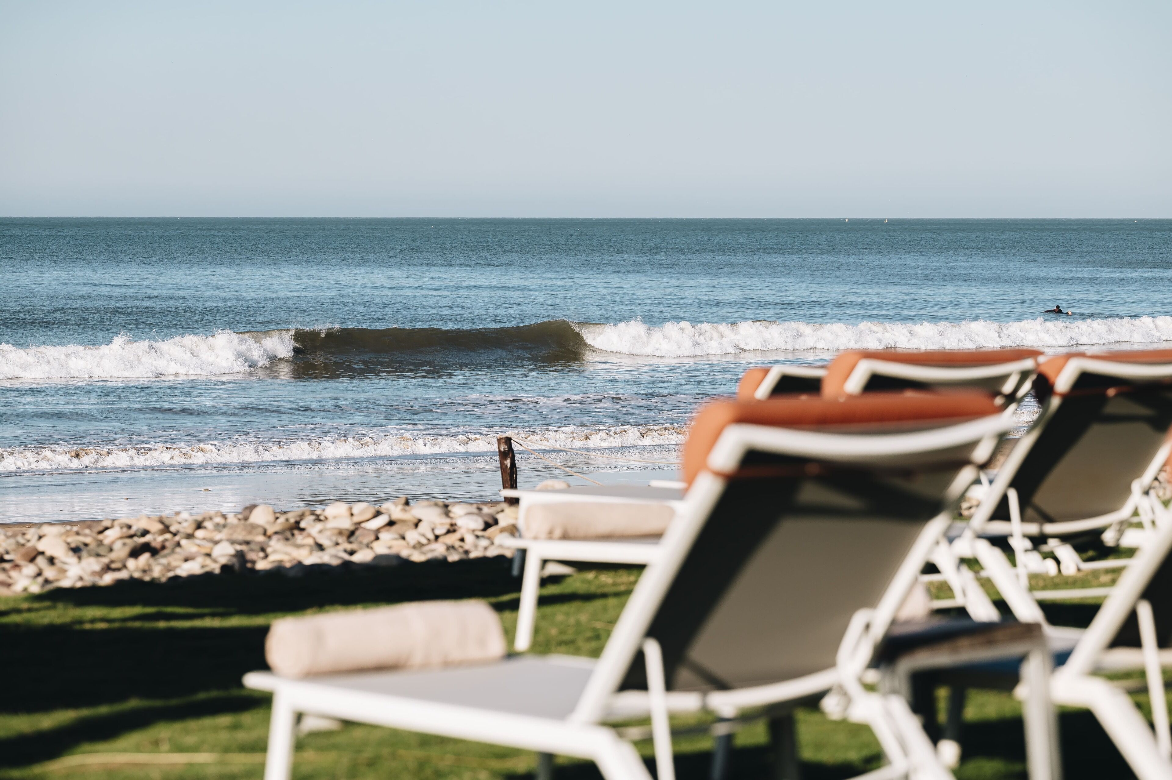 A beach view with lounge chairs and a rocky shoreline.