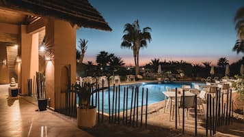 Una piscina al aire libre, sombrillas, sillones reclinables de piscina