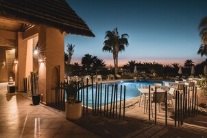 Una piscina al aire libre, sombrillas, sillones reclinables de piscina