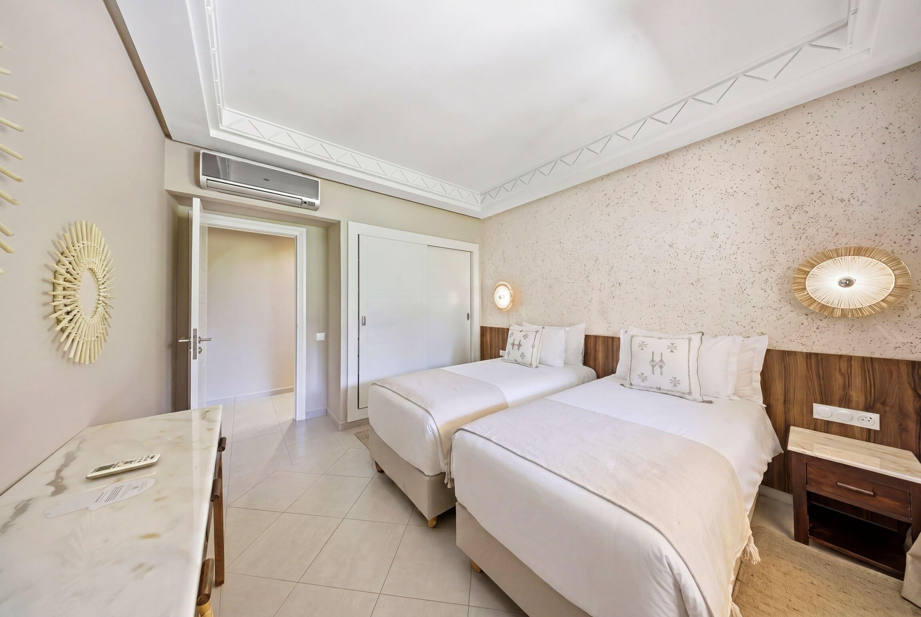 Ein Hotelzimmer mit zwei Betten, einem Schreibtisch, einem Stuhl, einem Kleiderschrank und einer Badezimmertür.