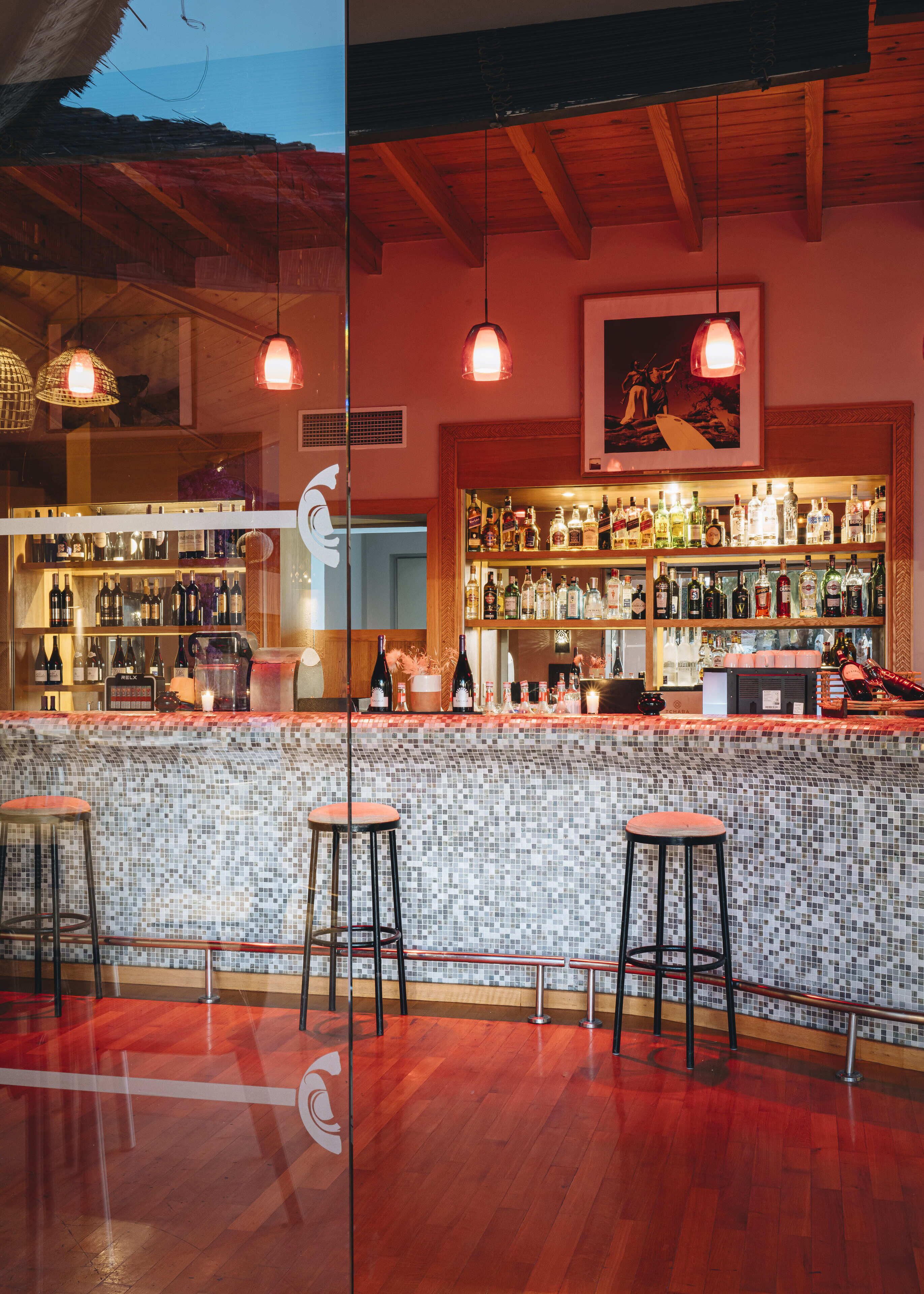 A bar area with a tiled backsplash, wooden bar counter, and stools.