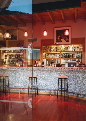 A bar area with a tiled backsplash, wooden bar counter, and stools.