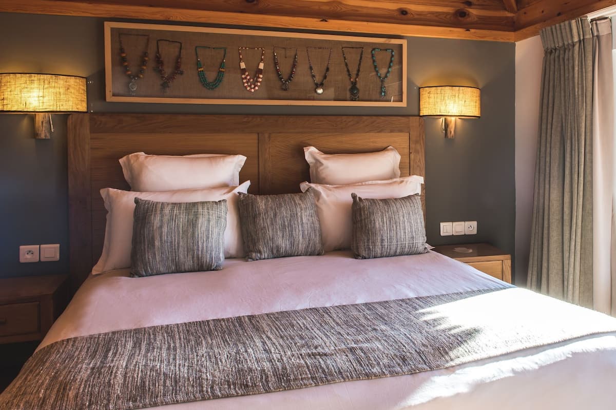 A bed with a wooden headboard, multiple pillows, and a decorative wall piece above.