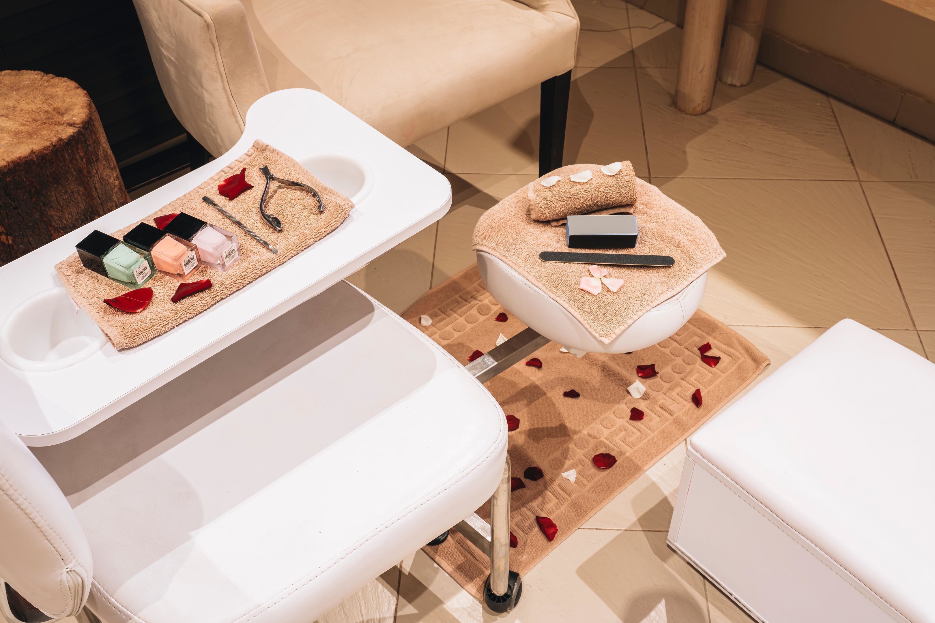A spa area with a white bathtub, a white chair, and a small table with bath products and a towel.