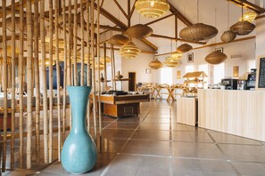 A spacious interior with high ceilings, bamboo partitions, and a central island with a coffee machine. - Paradis Plage Surf Yoga & Spa resort (Tamri)