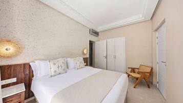 A bedroom with a large bed, a wooden nightstand, a chair, and a wardrobe.