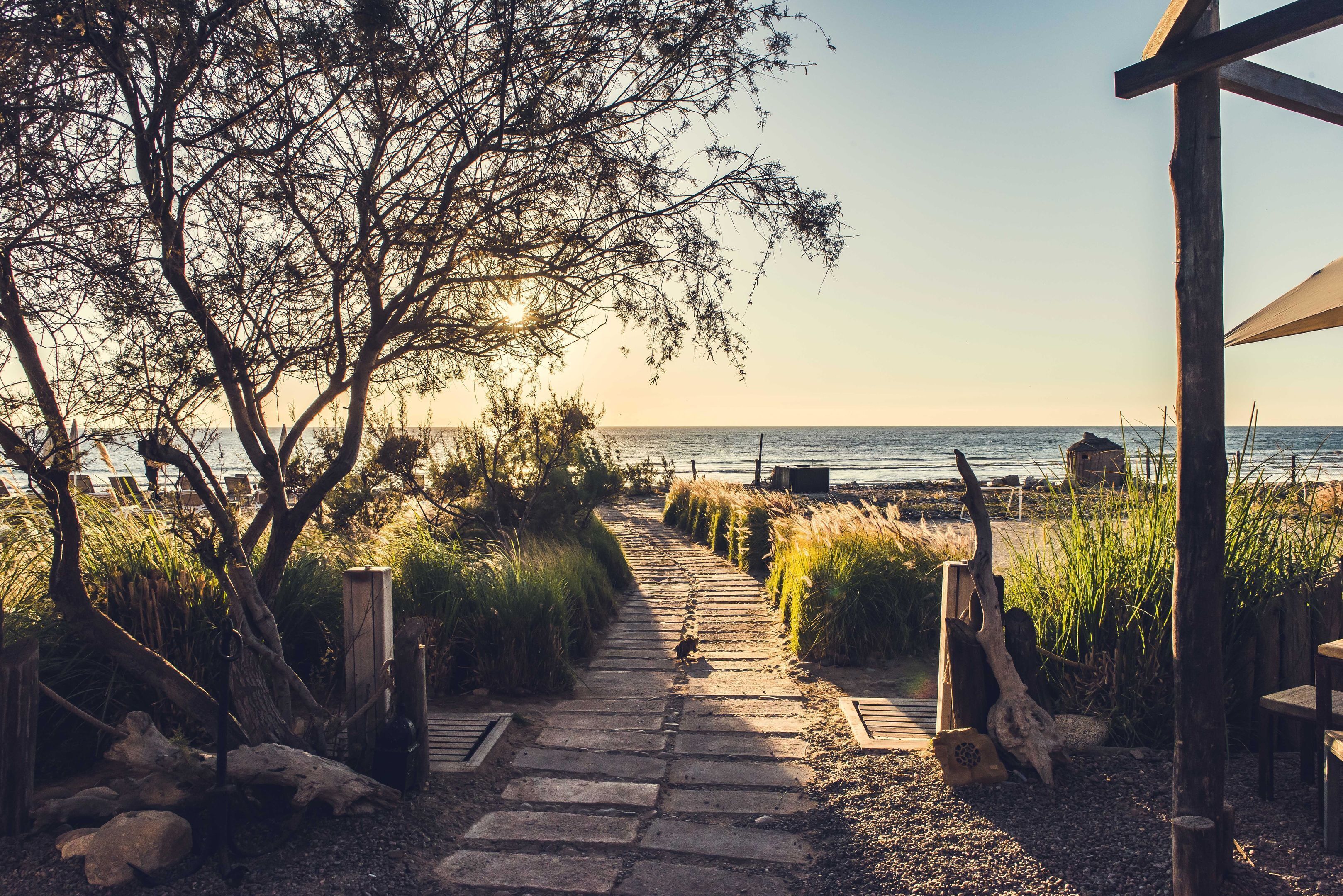 A stone pathway leading to a beach with a wooden structure on the right.