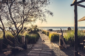 A stone pathway leading to a beach with a wooden structure on the right. - Paradis Plage Surf Yoga & Spa resort (Tamri)