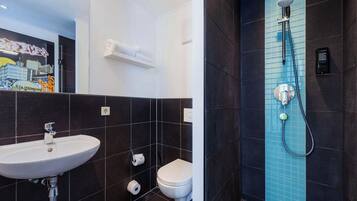 A modern bathroom with a white sink, toilet, and shower.