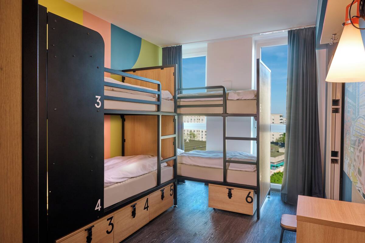 Habitació amb literes, vista a la ciutat, escriptori i làmpada.