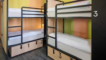Habitación con literas, tres camas en total, cada una con estructura de madera y un número.