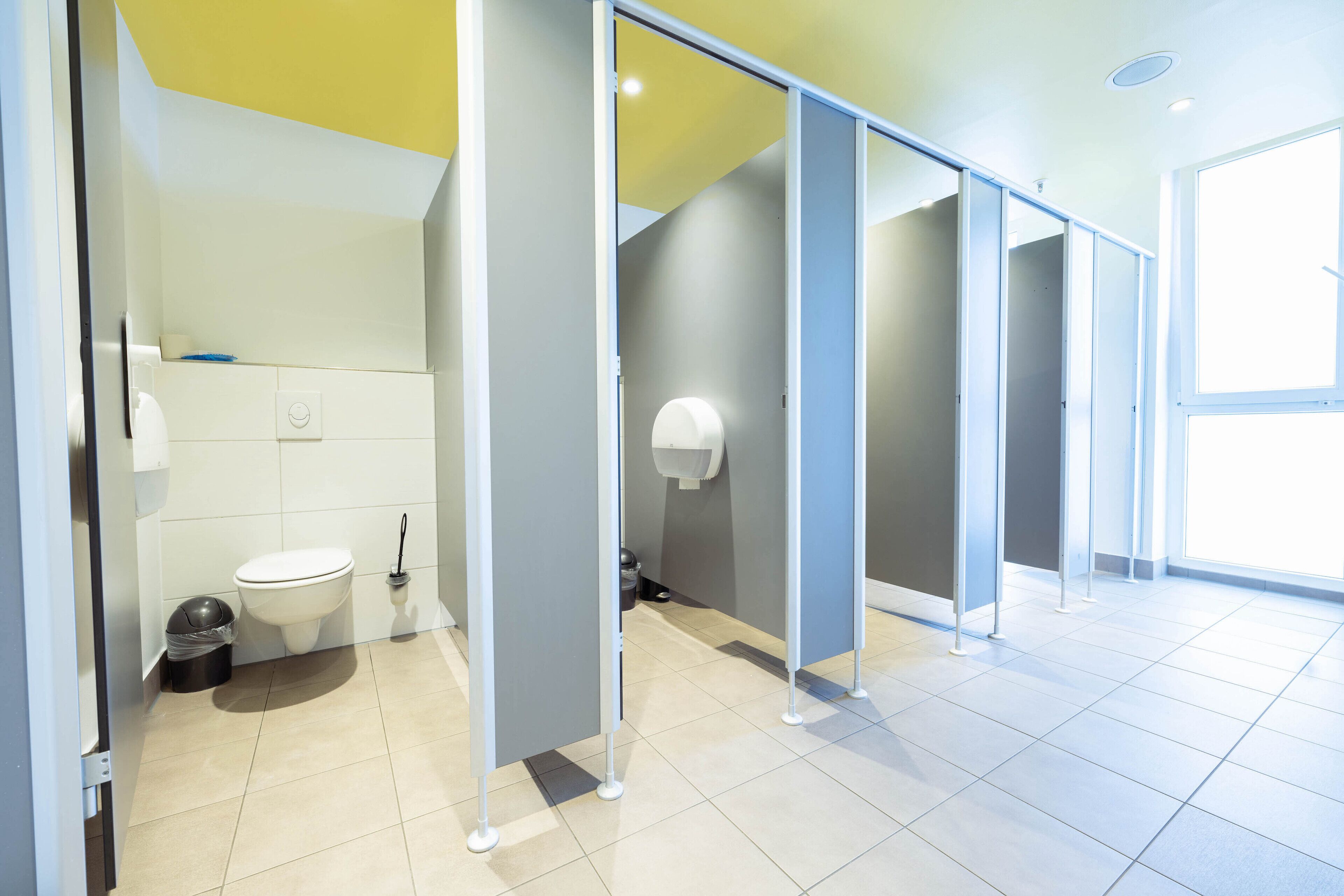 Baño moderno con inodoro, cubo de basura y secamanos.