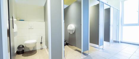 Baño moderno con inodoro, cubo de basura y secamanos.
