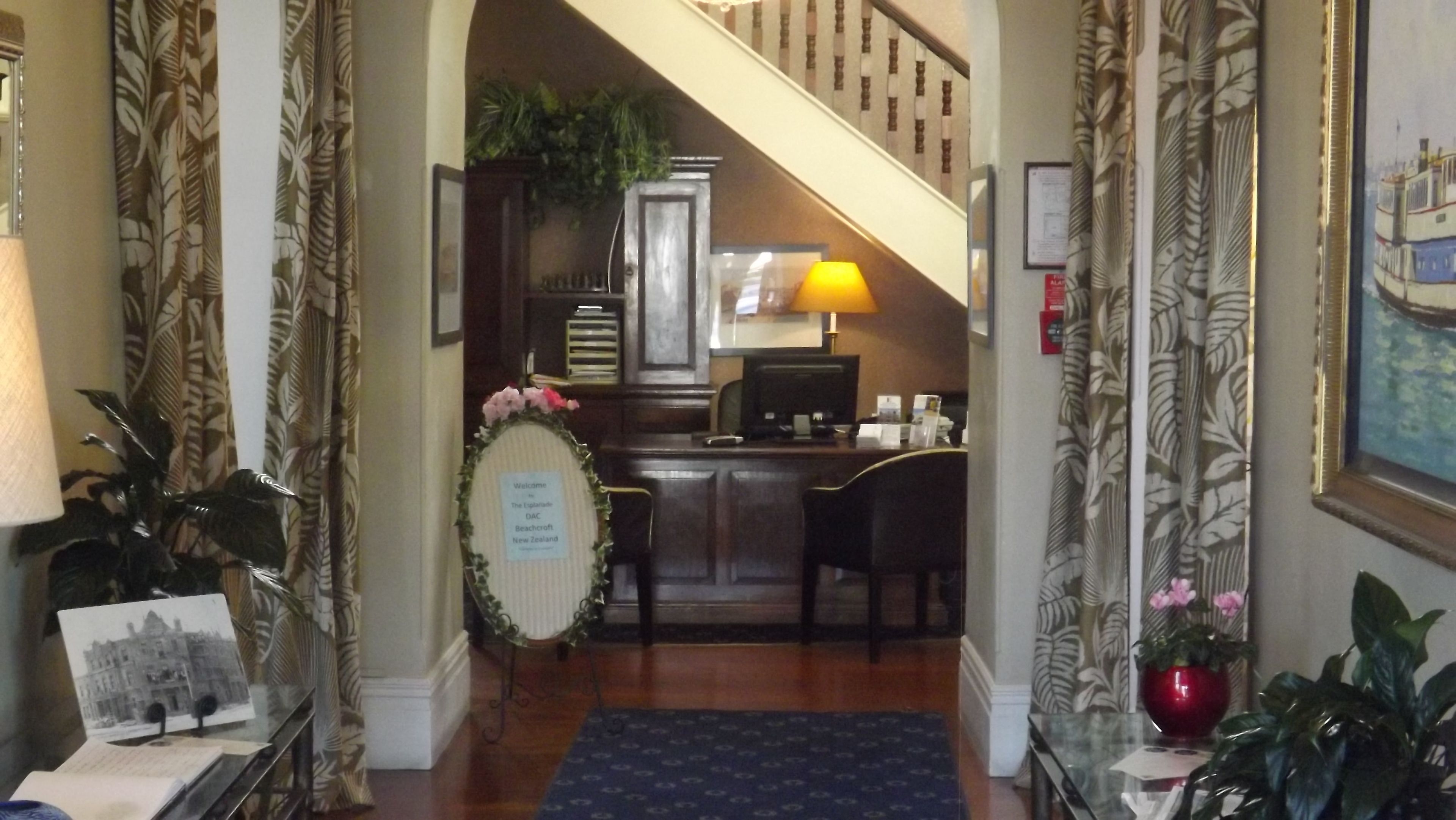 A reception area with a desk, a computer, a lamp, and a staircase leading to another floor.