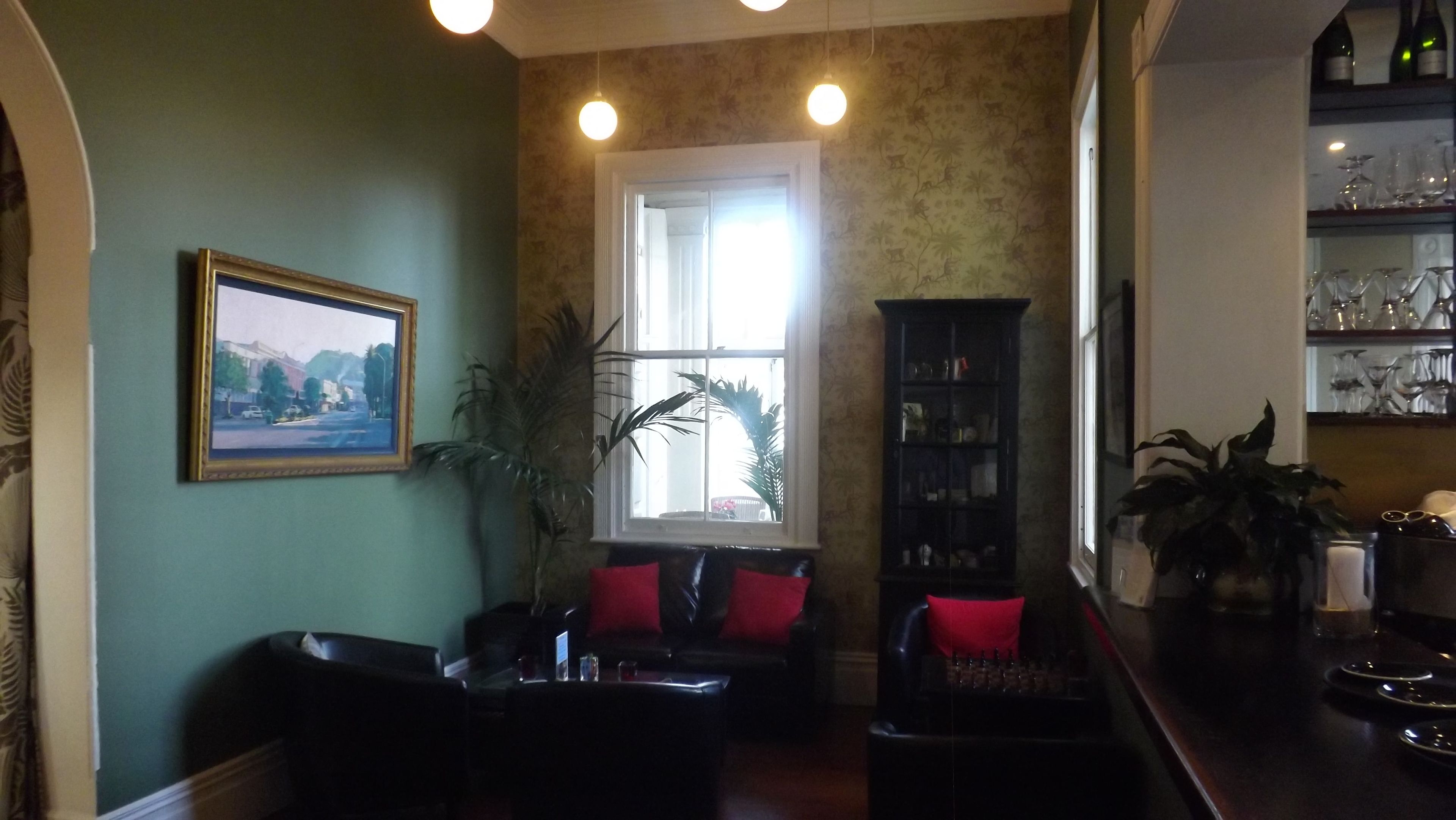 A cozy living room with a sofa, a coffee table, and a bookshelf. There is a window with a view of the outside, and a framed picture on the wall.