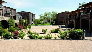 En modern byggnadskomplex med flera konstruktioner i trä, en central innergård med grönska och en gångbro för fotgängare.