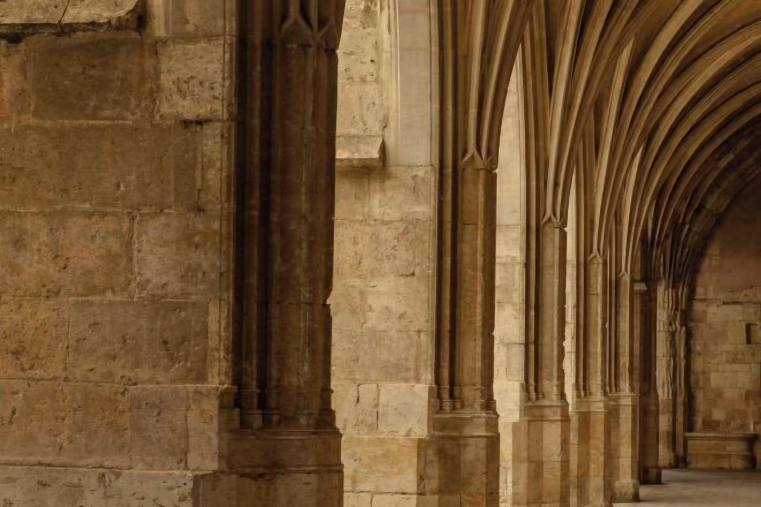 Un couloir en pierre, orné d’arcs en ogive et de colonnes, typique de l’architecture gothique.